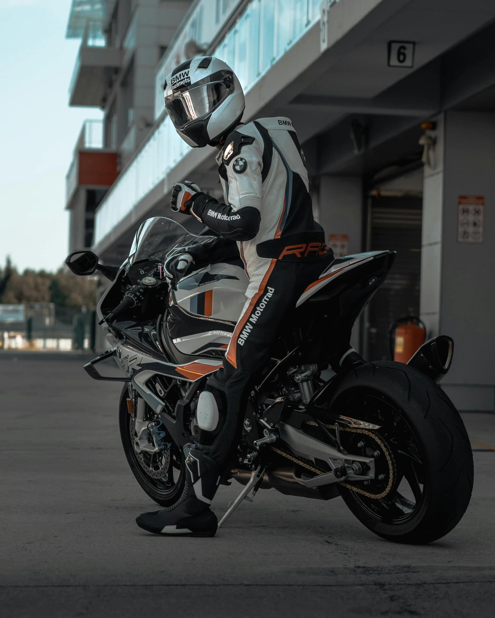 the motorcyclist is wearing a white, orange and black helmet