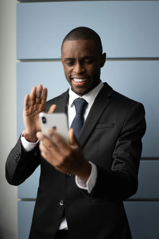 a man in suit holding up a smart phone