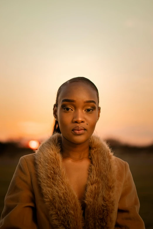 a woman with a jacket is sitting outside at sunset