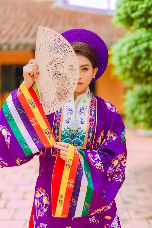 a girl in traditional clothes holding a fan