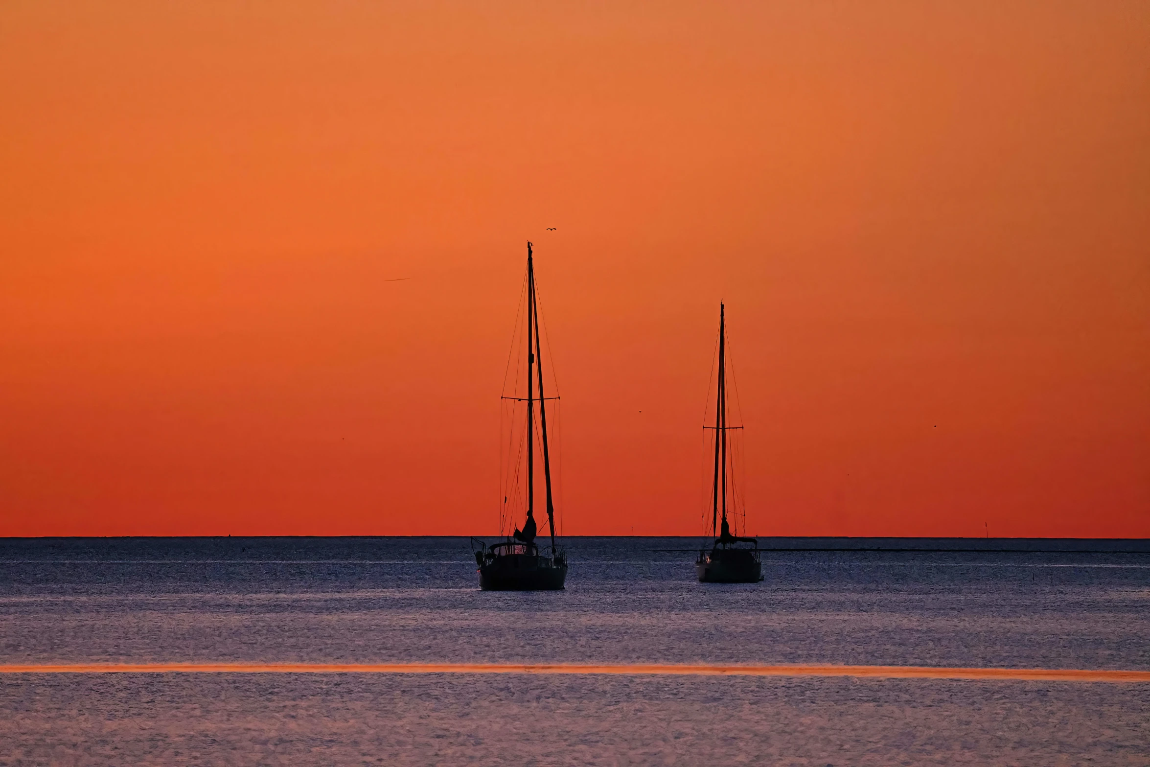 two boats are seen out on the ocean at sunset