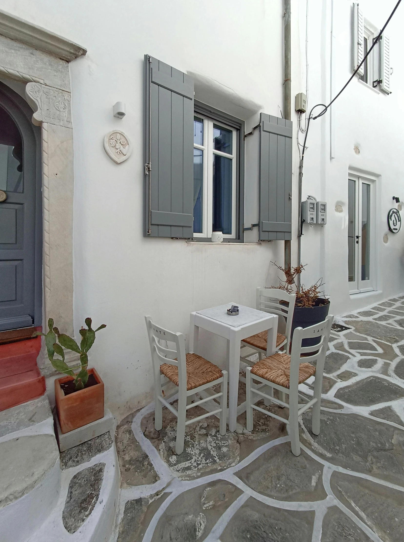 a small patio with table and chairs is situated in front of a house