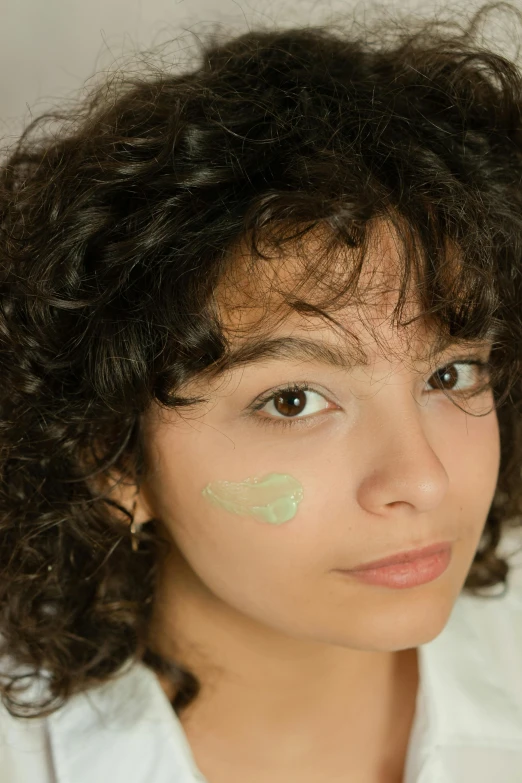 a woman with a green mask has curly hair and is looking to the right