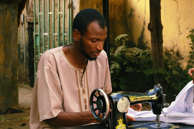 the black man is using a sewing machine