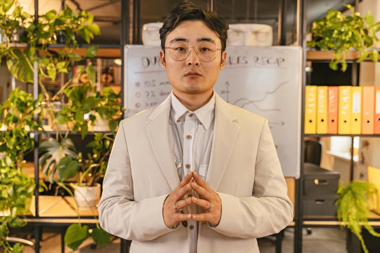 a man standing in front of a shelf with some green plants