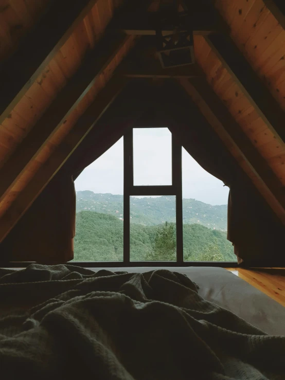 a bedroom view from an attic looking down at mountains