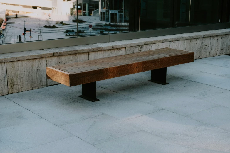 a bench sitting on the concrete by a window