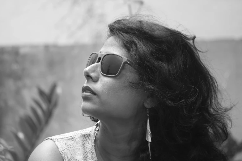 a woman with long hair wearing sunglasses near a wall