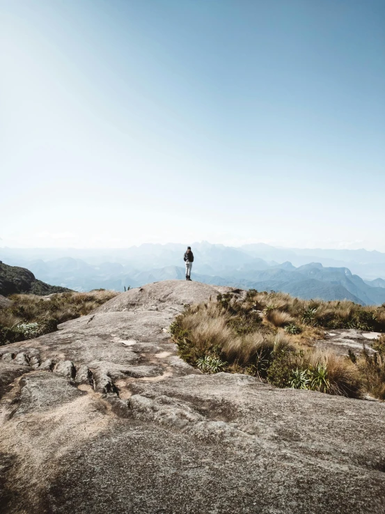 a hiker stands on the edge of a grassy hill