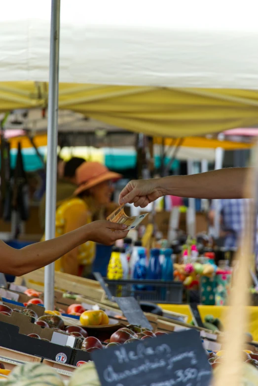 two people exchanging food from a man in an open market