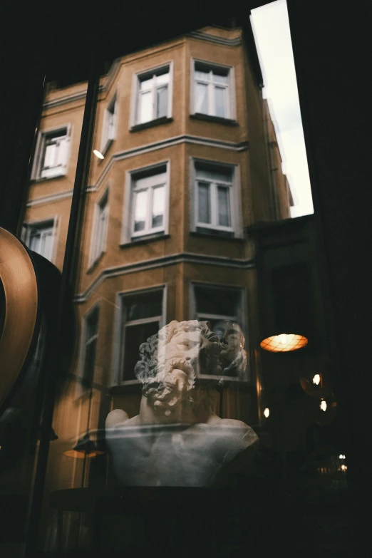 looking out a window at a building with an illuminated bust in front