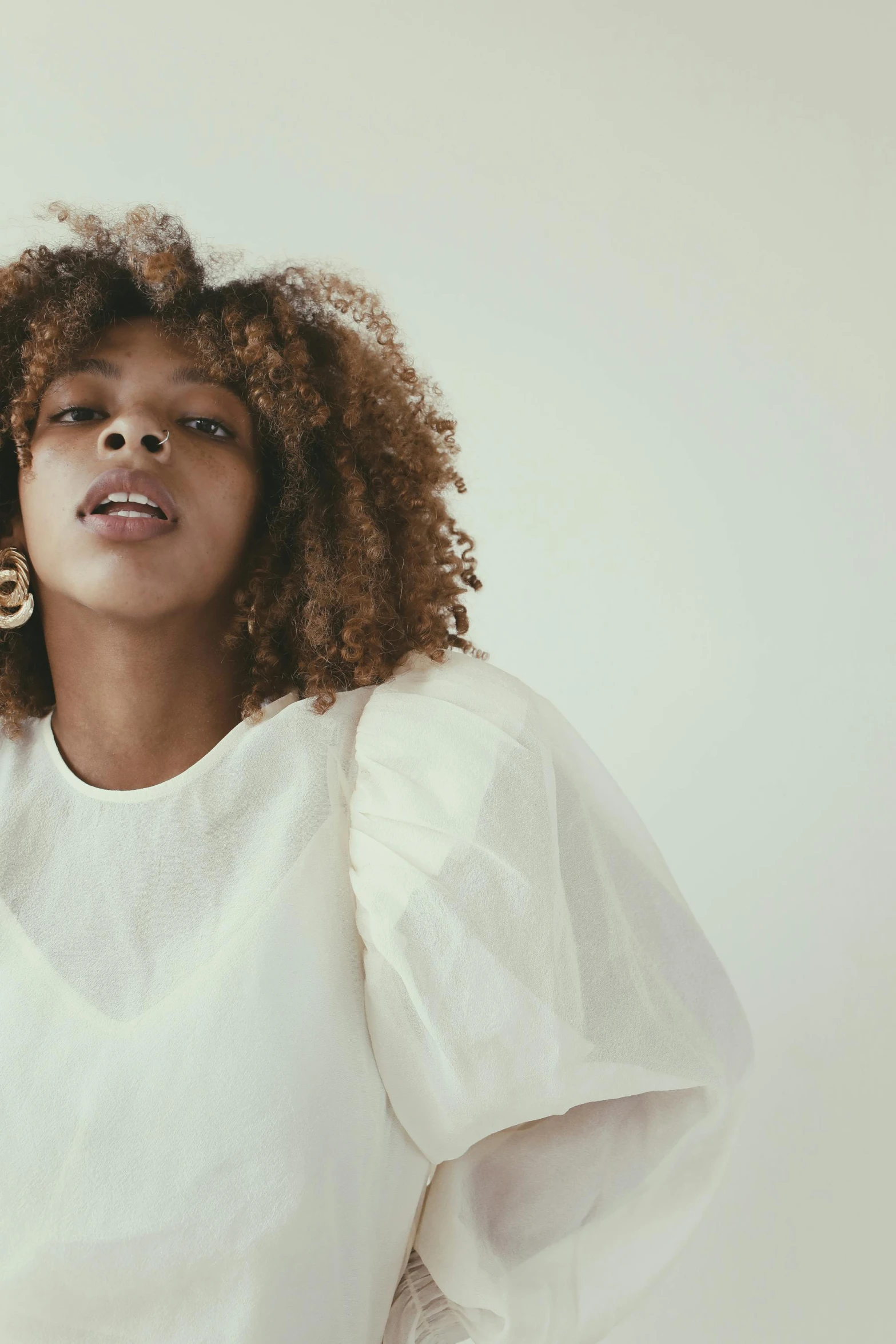 a model wears a white sweater with an afro and earrings