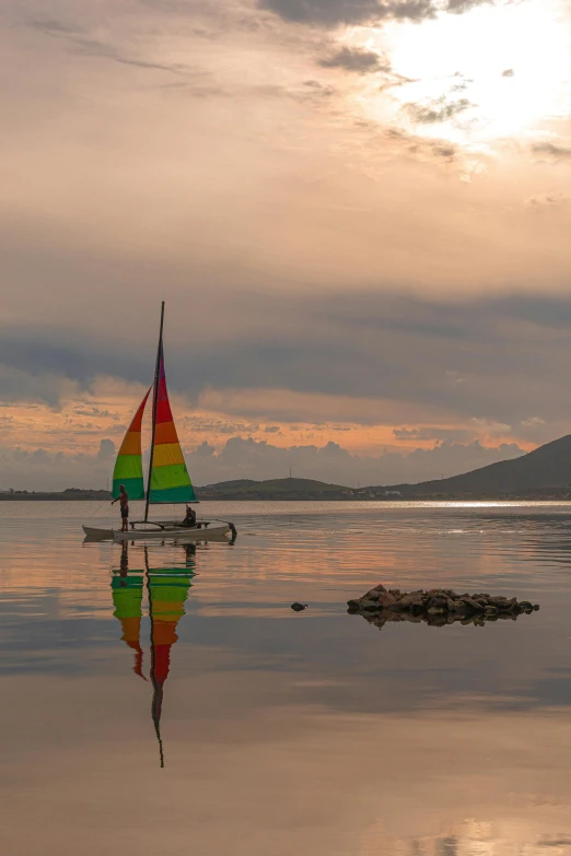 a colorful sail boat sitting on top of a large body of water