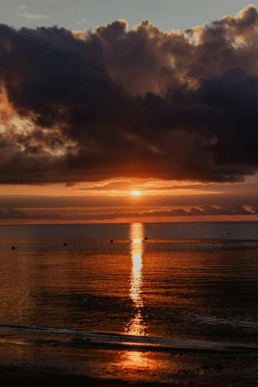 the sun is setting at a very large body of water