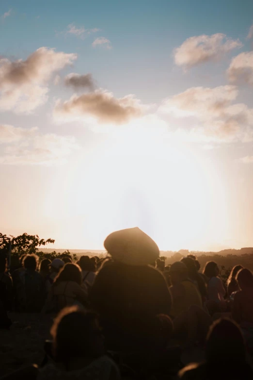 the sun is shining behind people standing in front of a cloudy sky