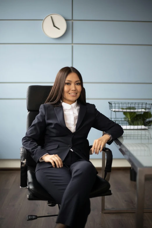 a woman in a black jacket and white shirt sitting in an office chair