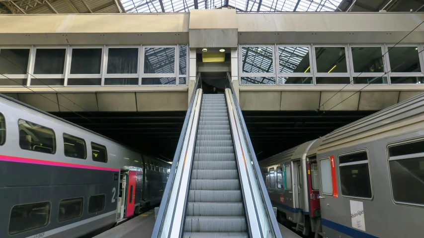 two trains with passengers going up and down the escalator