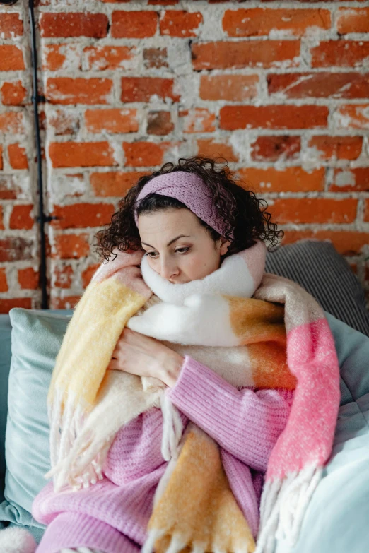 woman wrapped in blanket and wool headband sitting on bed