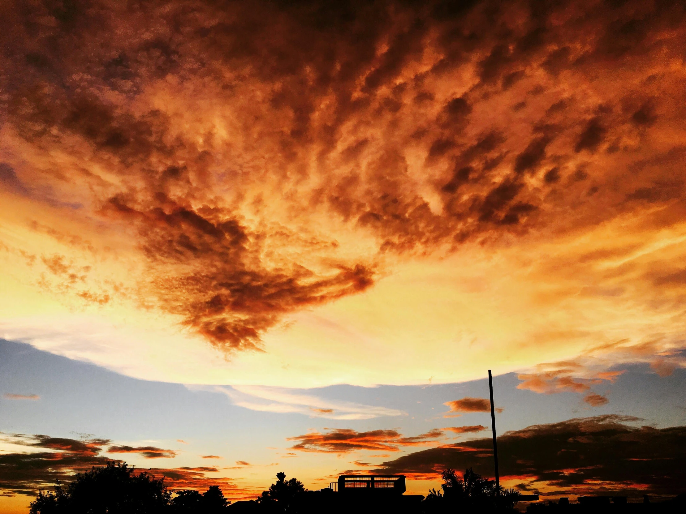 clouds are shown over some buildings at sunset