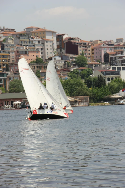 boats are sailing through the water in front of some city buildings