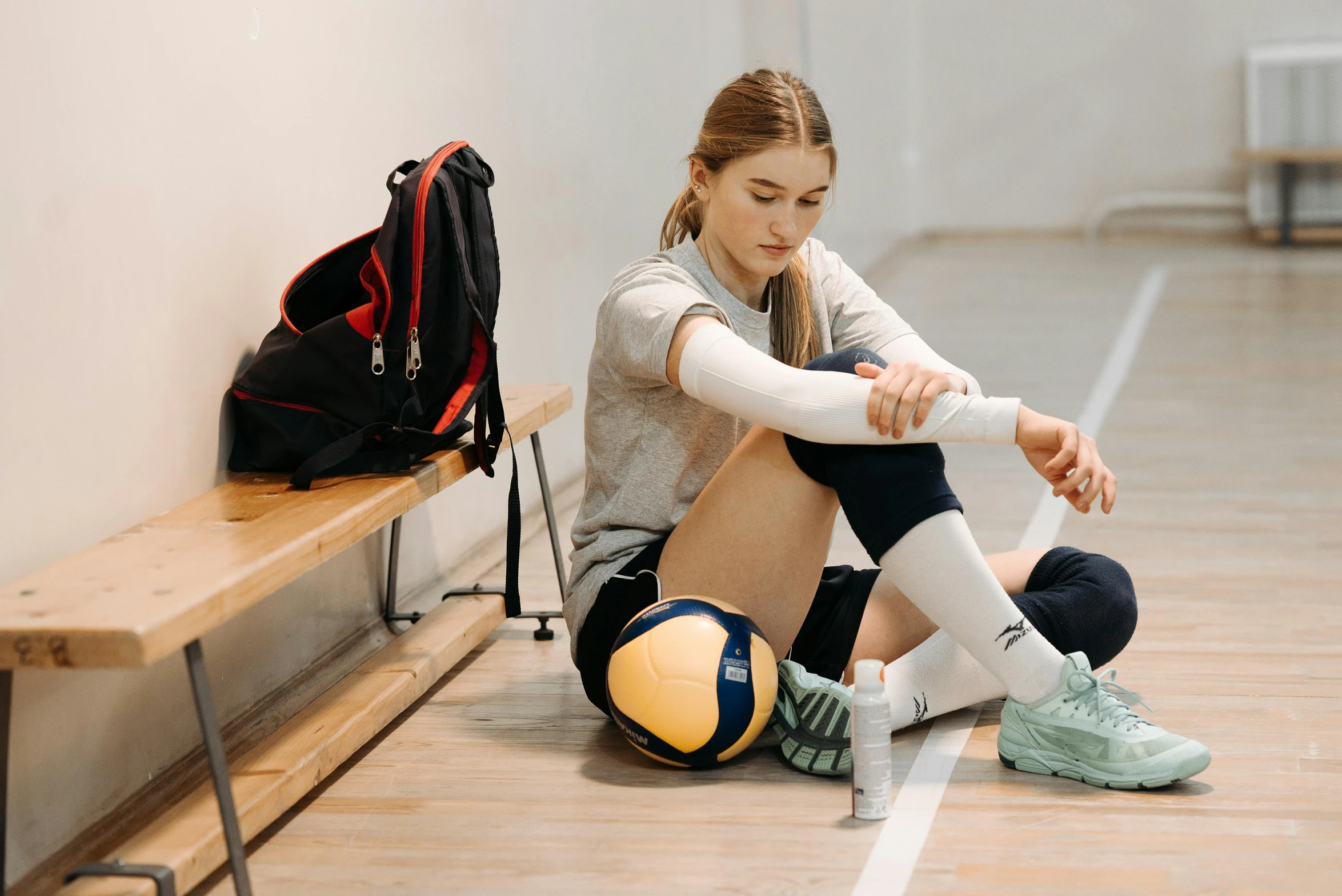 a girl with a cast is resting on the floor next to a ball