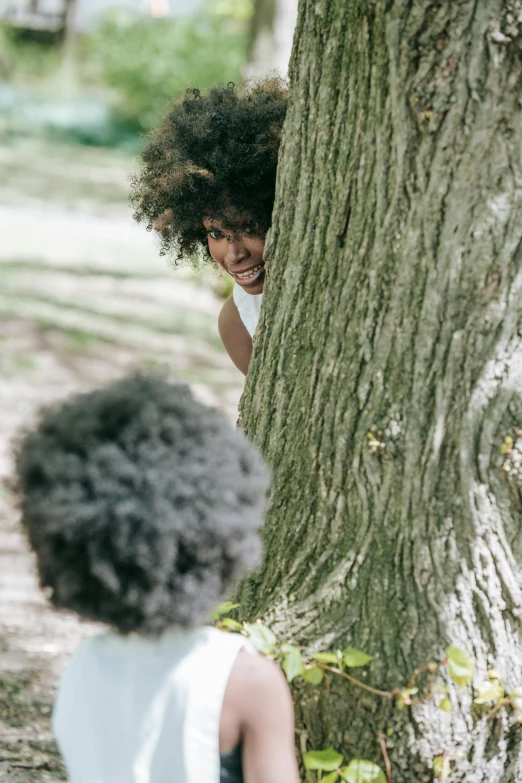 two girls are hugging a tree in the park