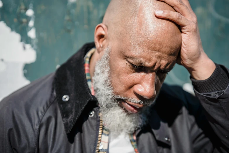 a man with a bald head and grey beard wearing black jacket