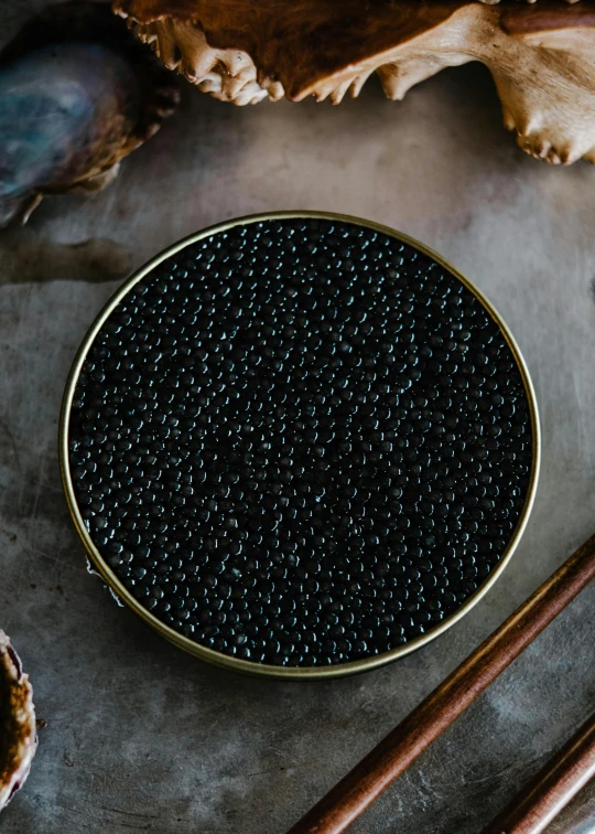 black beads sitting on a black plate next to chopsticks