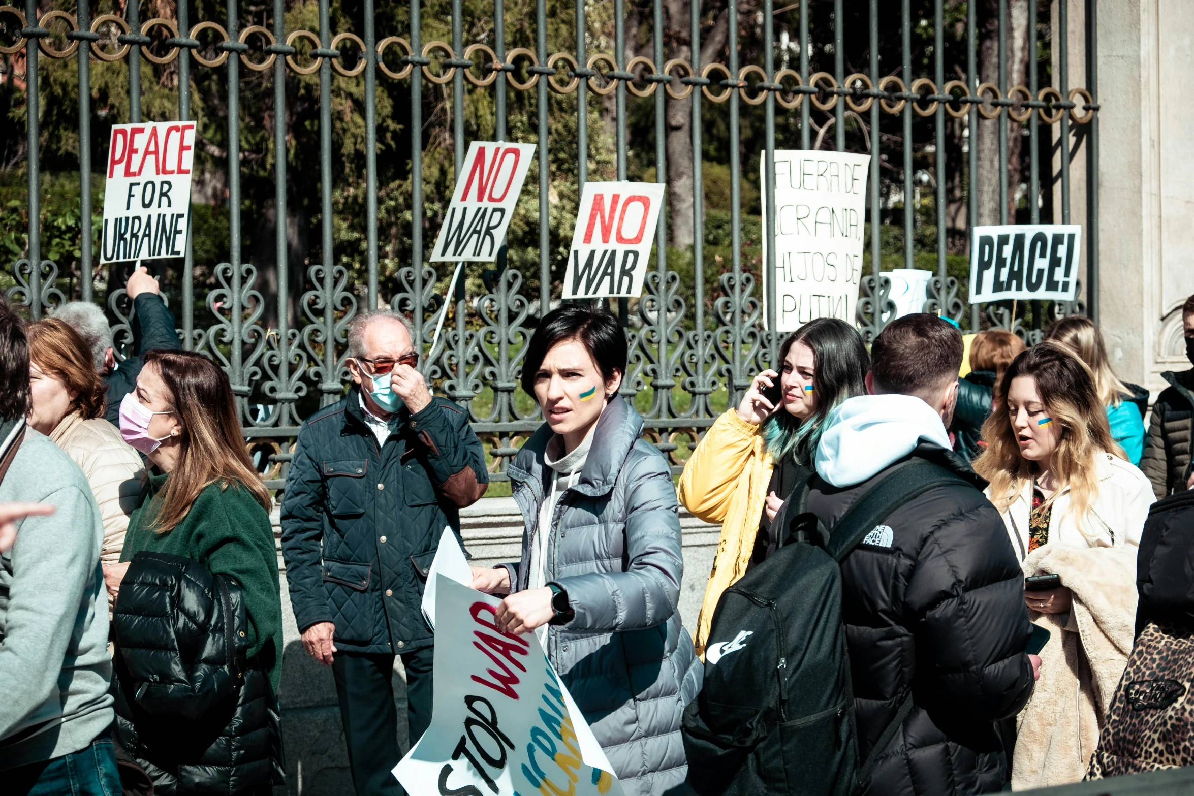 a woman holding a sign next to a fence