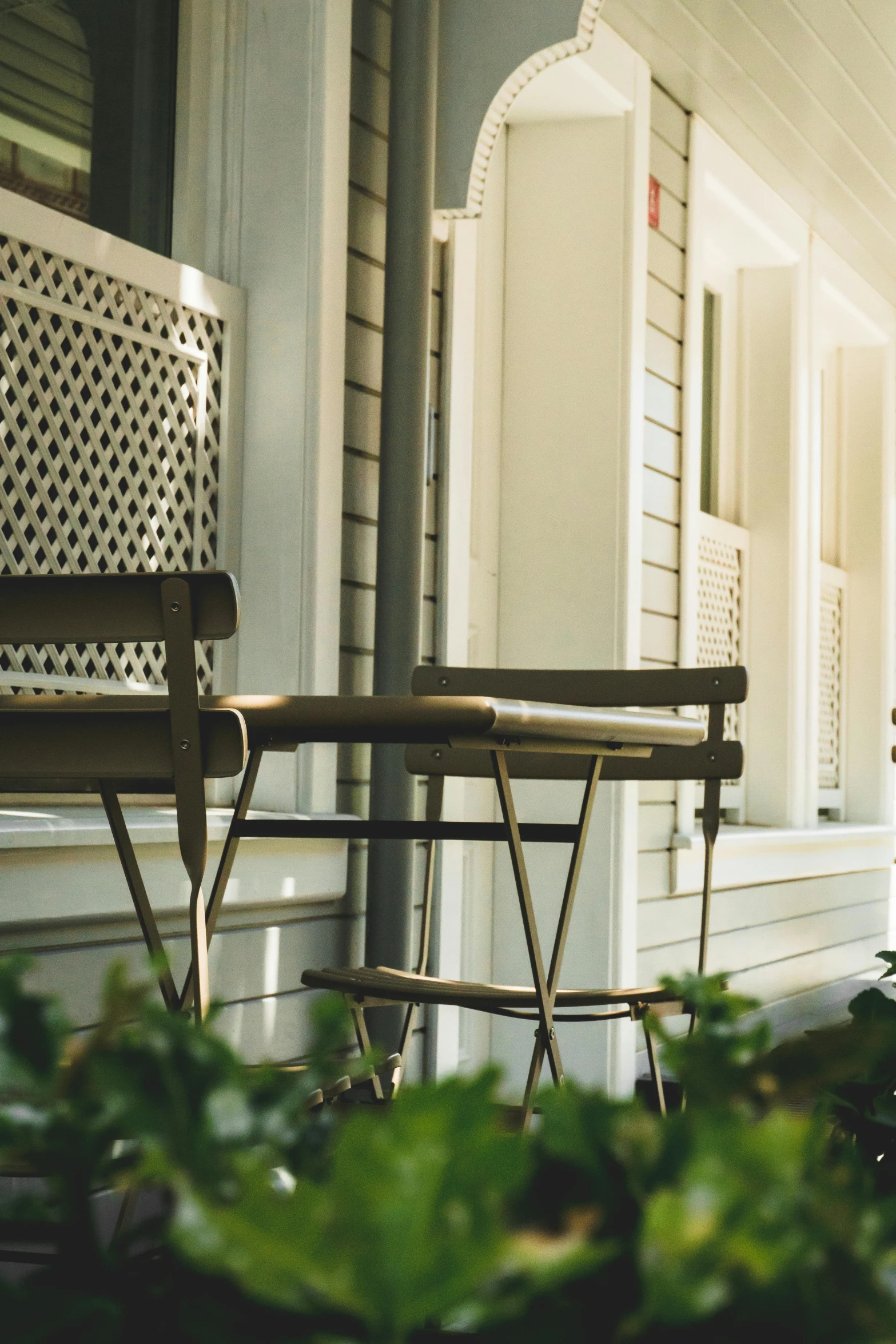 two wooden chairs sit outside on the porch