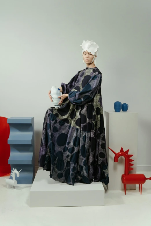 a woman sits on top of a shelf with a vase in her hand