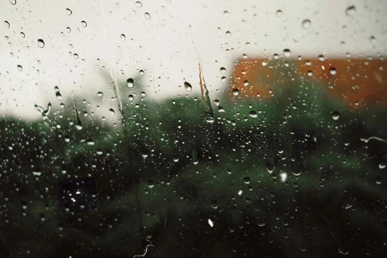 the view out of a rain covered window at an orange house