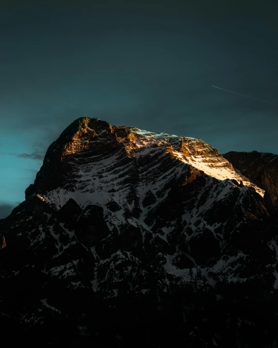 a snow capped mountain with a few cloud covered hills