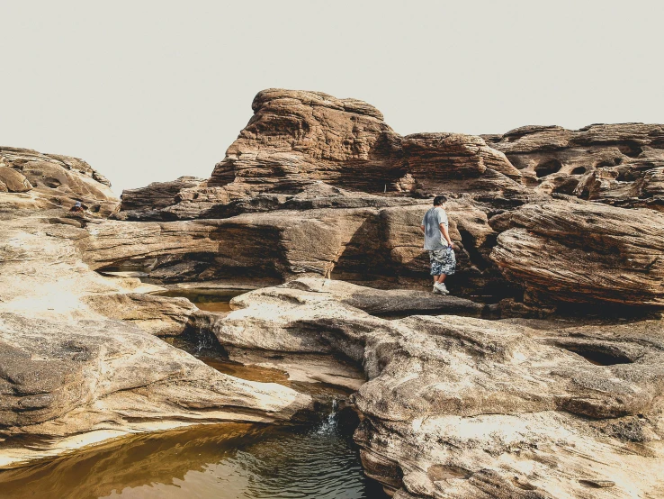 a man stands at the top of an overlook looking down on a large, rocky valley