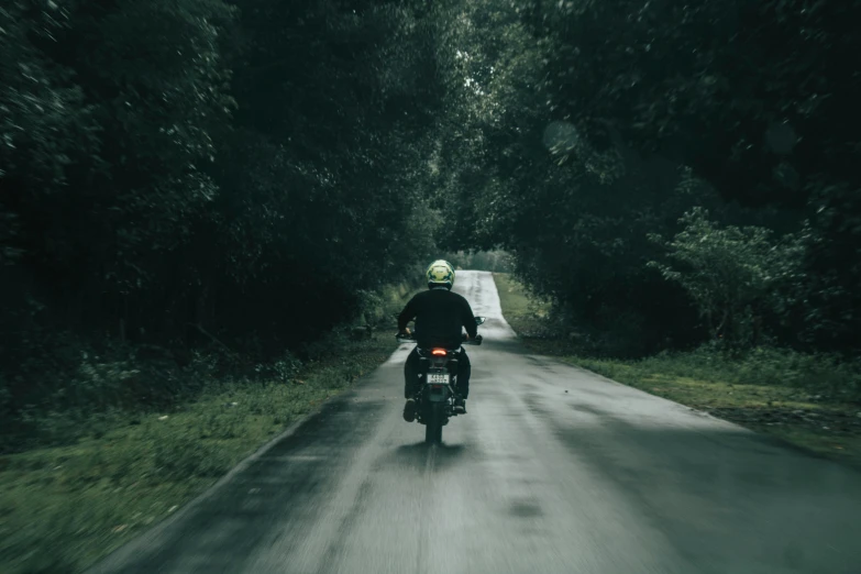 a man on a motorcycle riding down a paved road