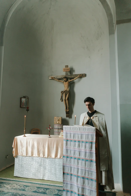 a man sitting down at a table with a cross above it