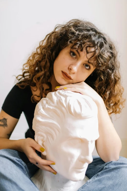 a woman sitting on the ground holding a white sculpture