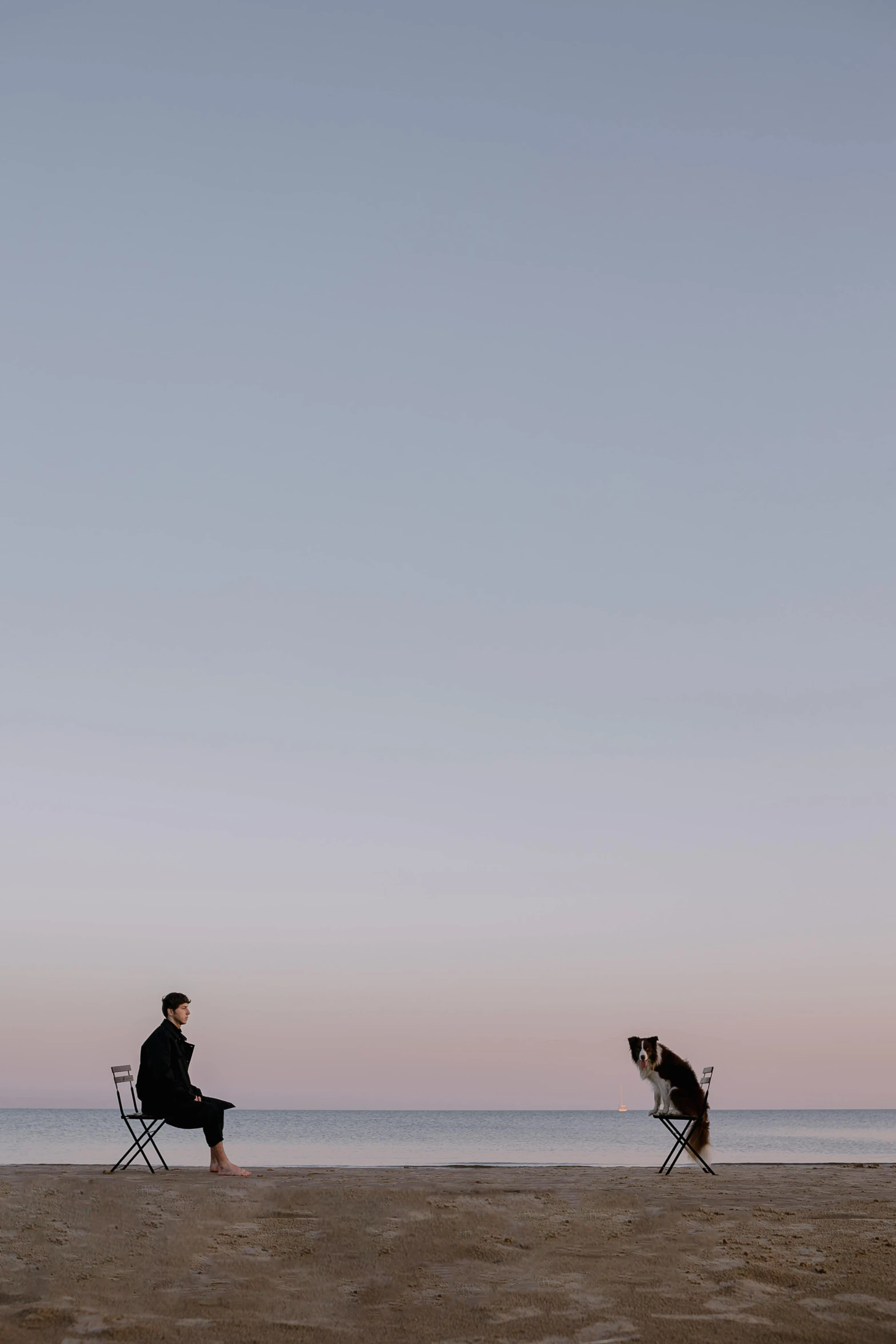 two men sitting on chairs on a beach