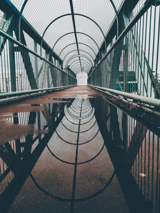 an old bridge with metal poles and poles is reflected in a dle