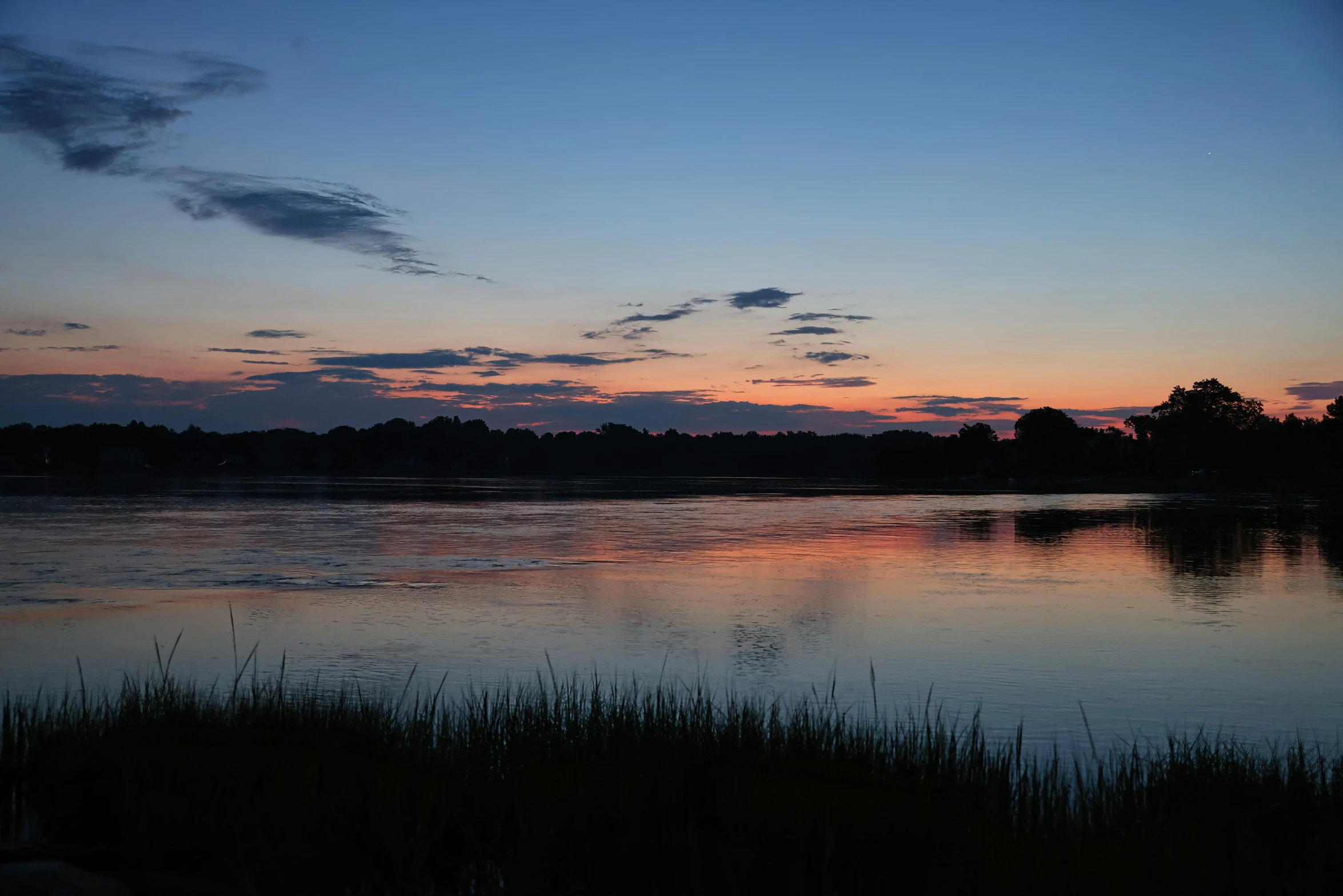 the sky is setting over the lake and water