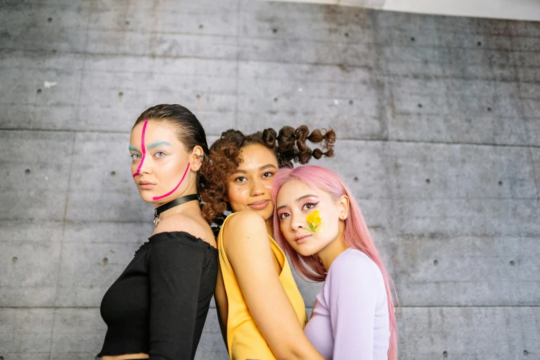 three females are posing for a pograph with their face painted