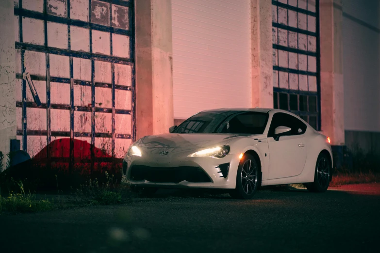 a white car parked in front of a building at night