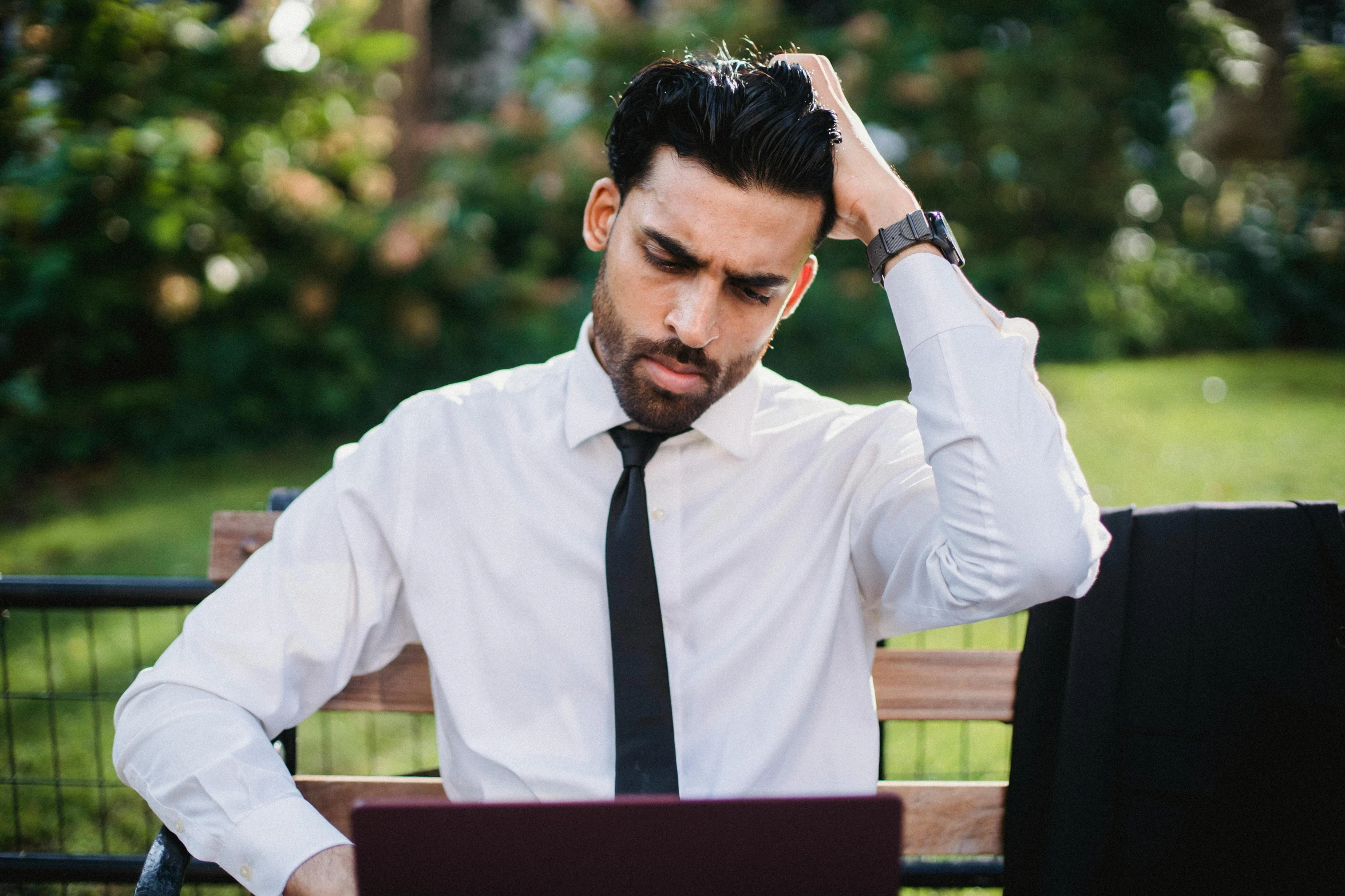 the man has his hands on his head as he looks at his computer