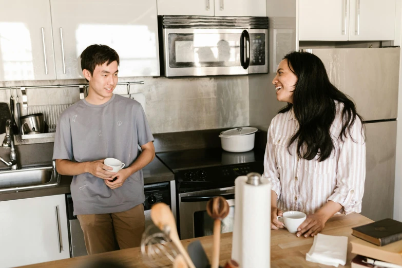 two people standing near each other in the kitchen