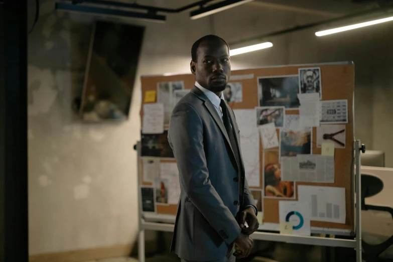 a man in a suit standing by a bulletin board