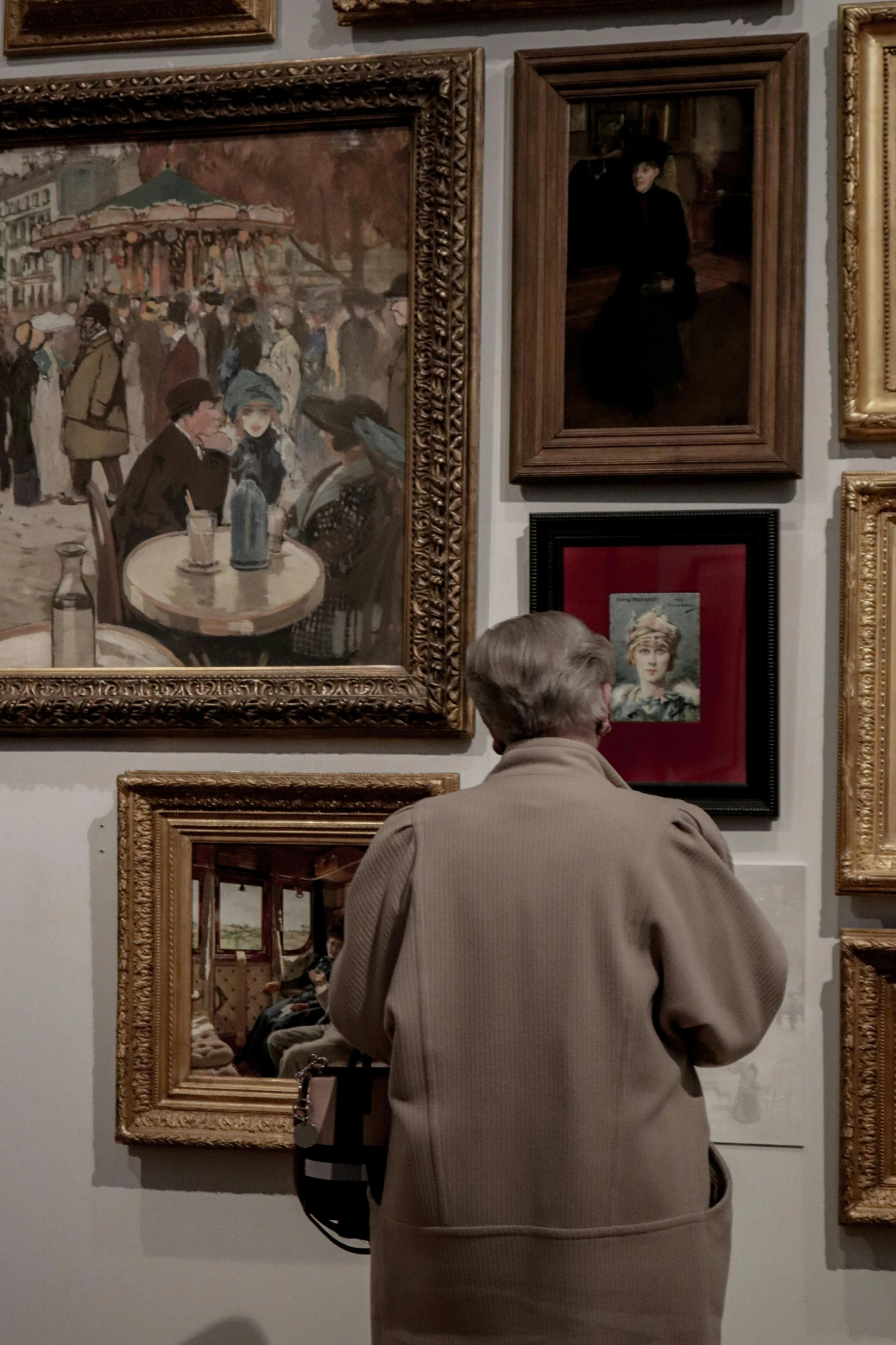 a woman standing next to framed pictures in front of a wall