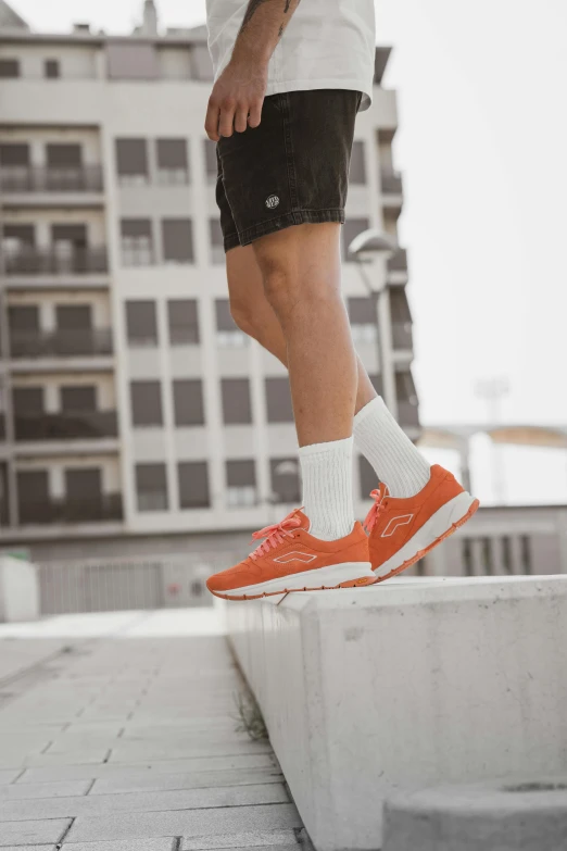 man wearing orange tennis shoes walking on brick path