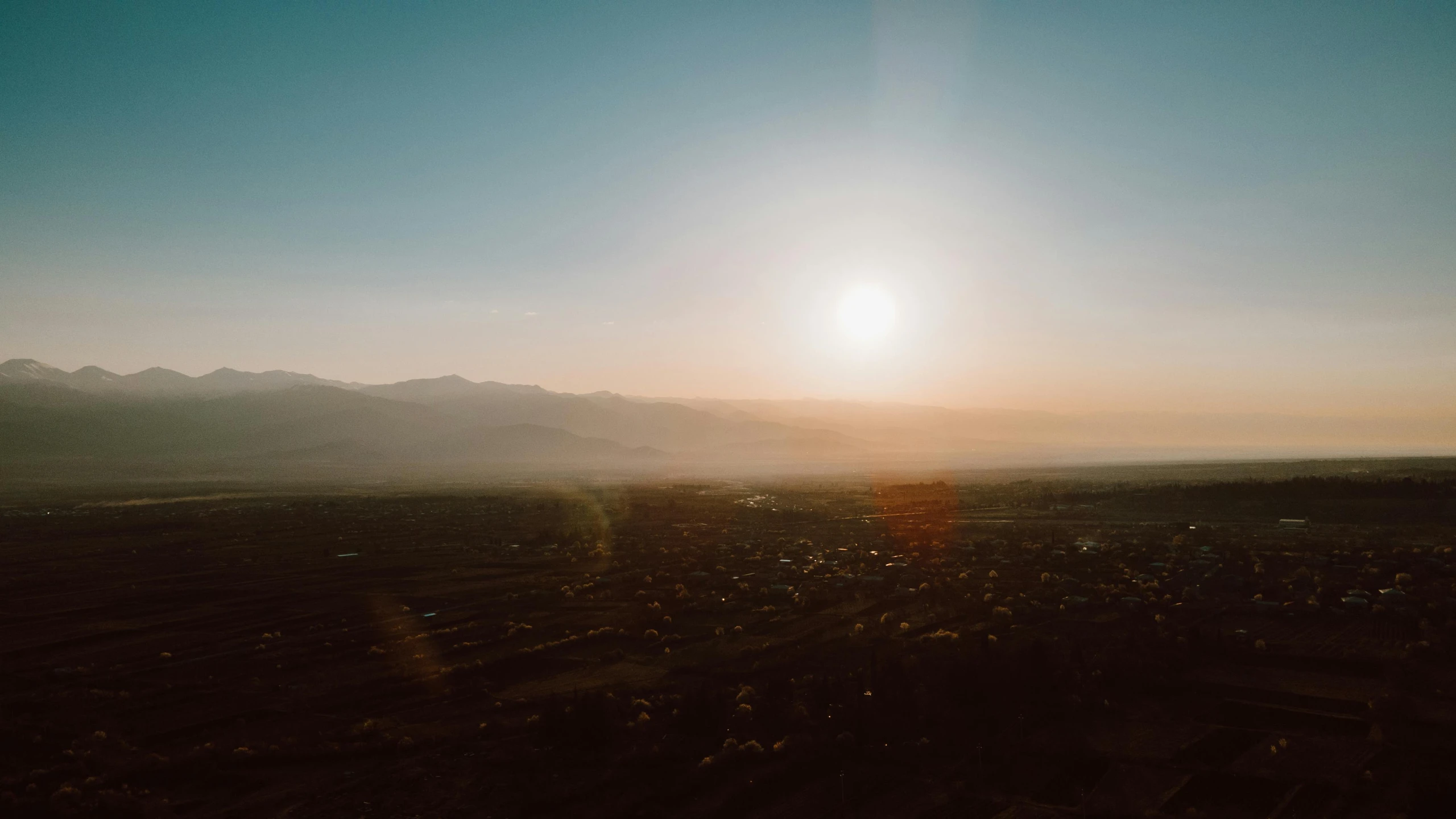 sun rising above a distant city and mountains