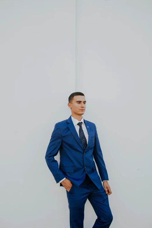 a man wearing a blue suit and white shirt is posing for the camera