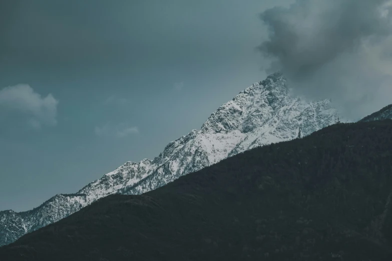 mountains with white capped snow are shown against a cloudy blue sky